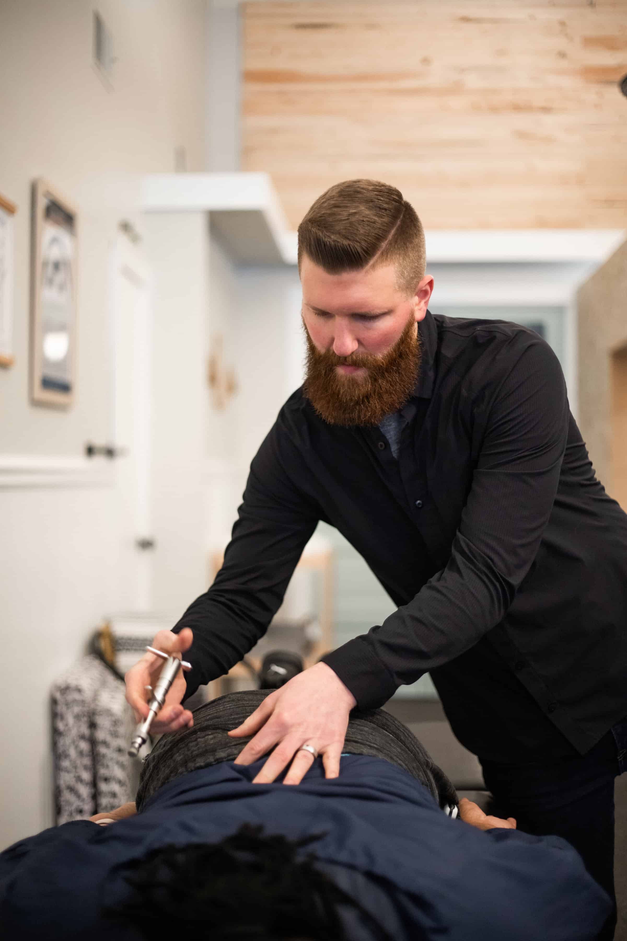 Chiropractor adjusted the back of a patient as they lie on a bench