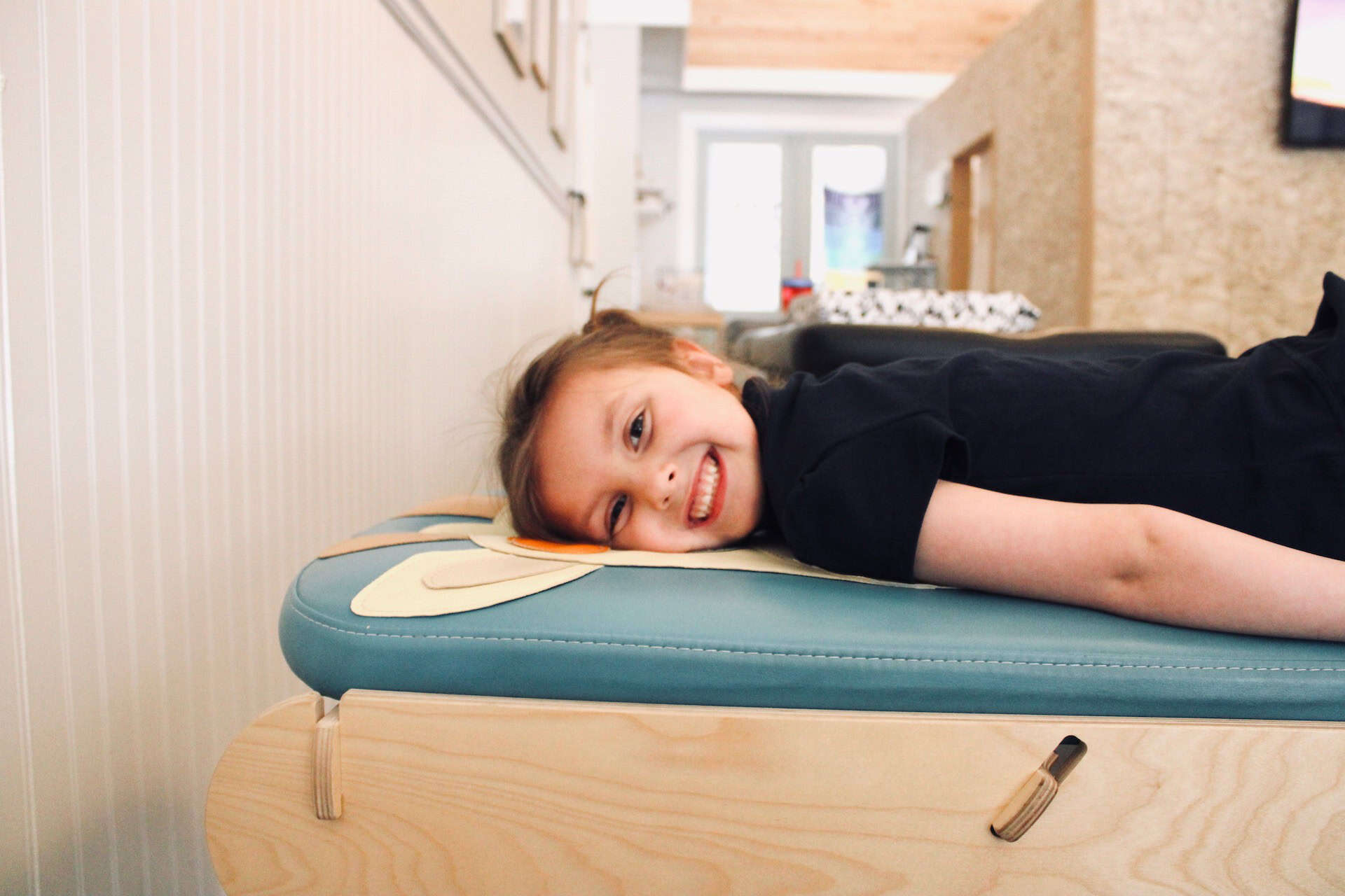 Photo of a girl smiling while lying on a bench for autism and chiropractic care
