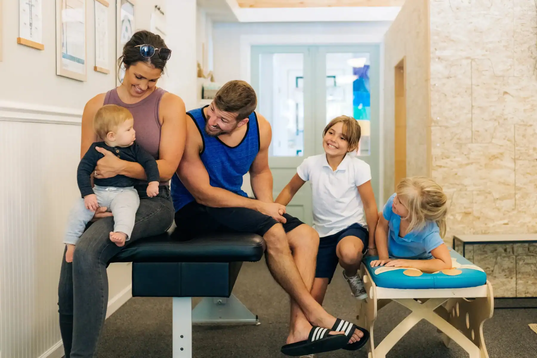 Photo of a smiling family sitting on benches in a chiropractor clinic