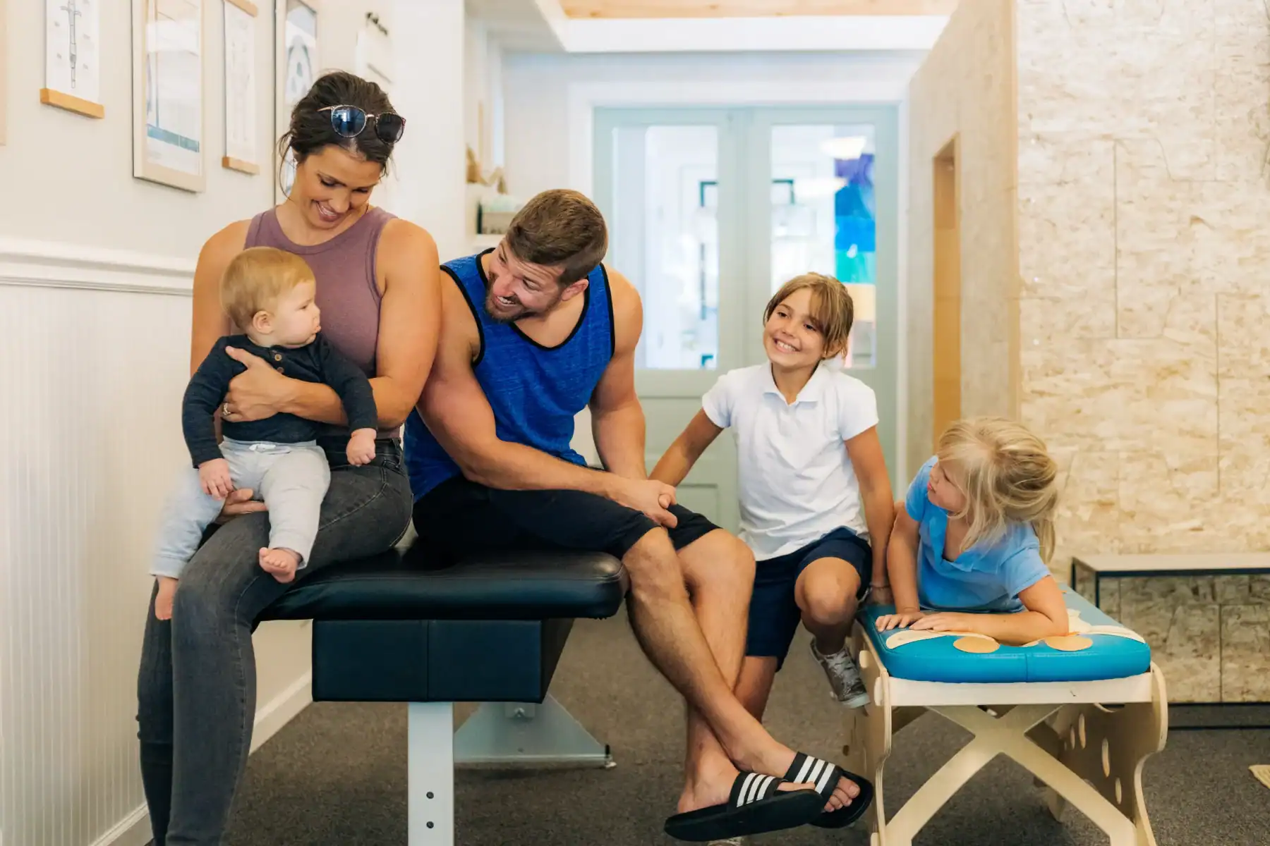 Photo of a smiling family sitting on benches in a chiropractor clinic