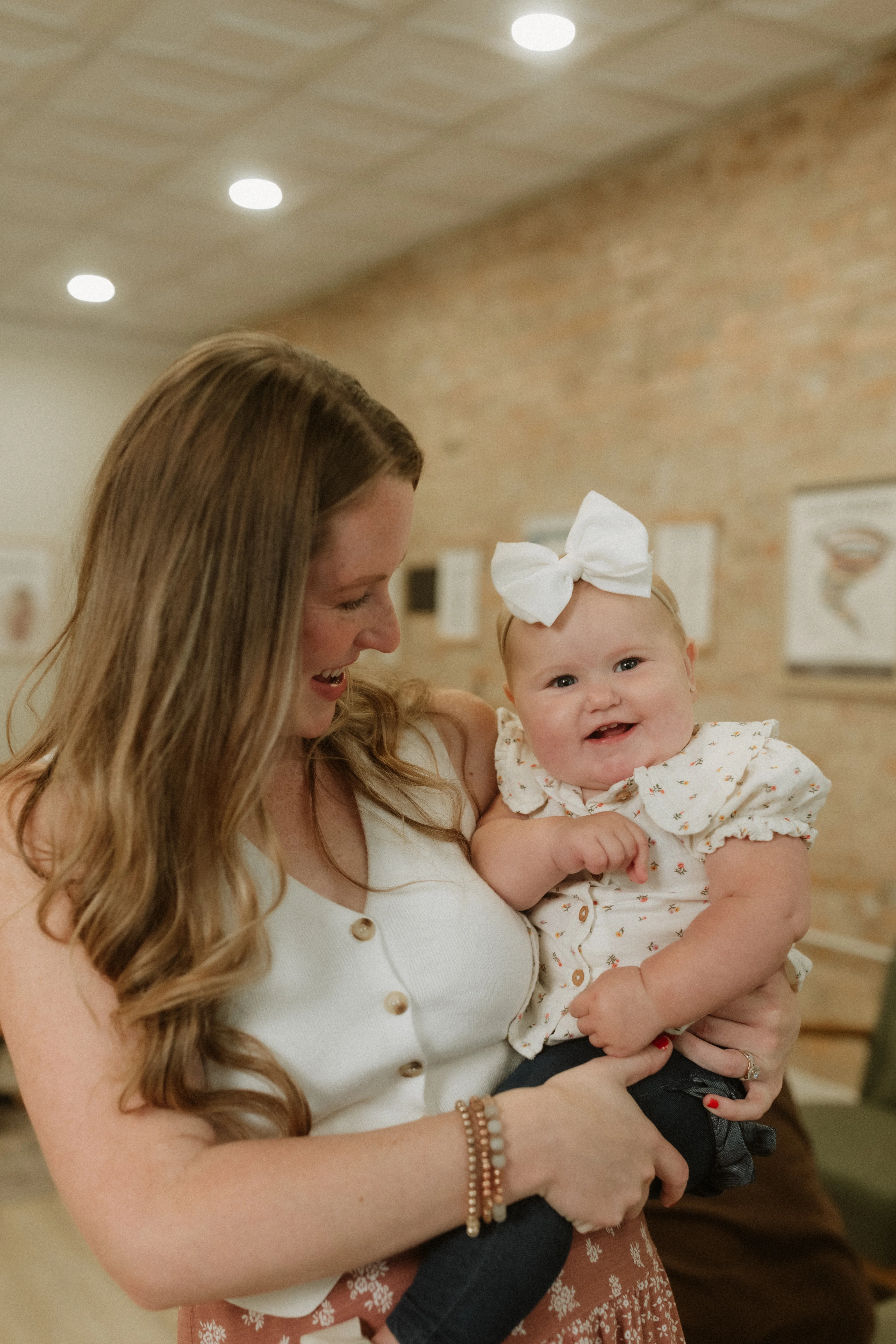 Photo of a mother smiling while holding her baby as she smiles at the camera in a chiropractic office