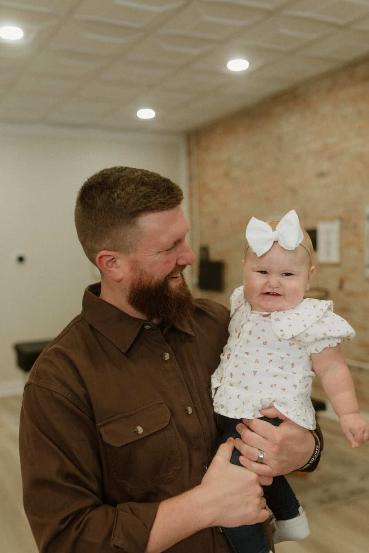 Photo of a father smiling while holding his baby in a chiropractor office.