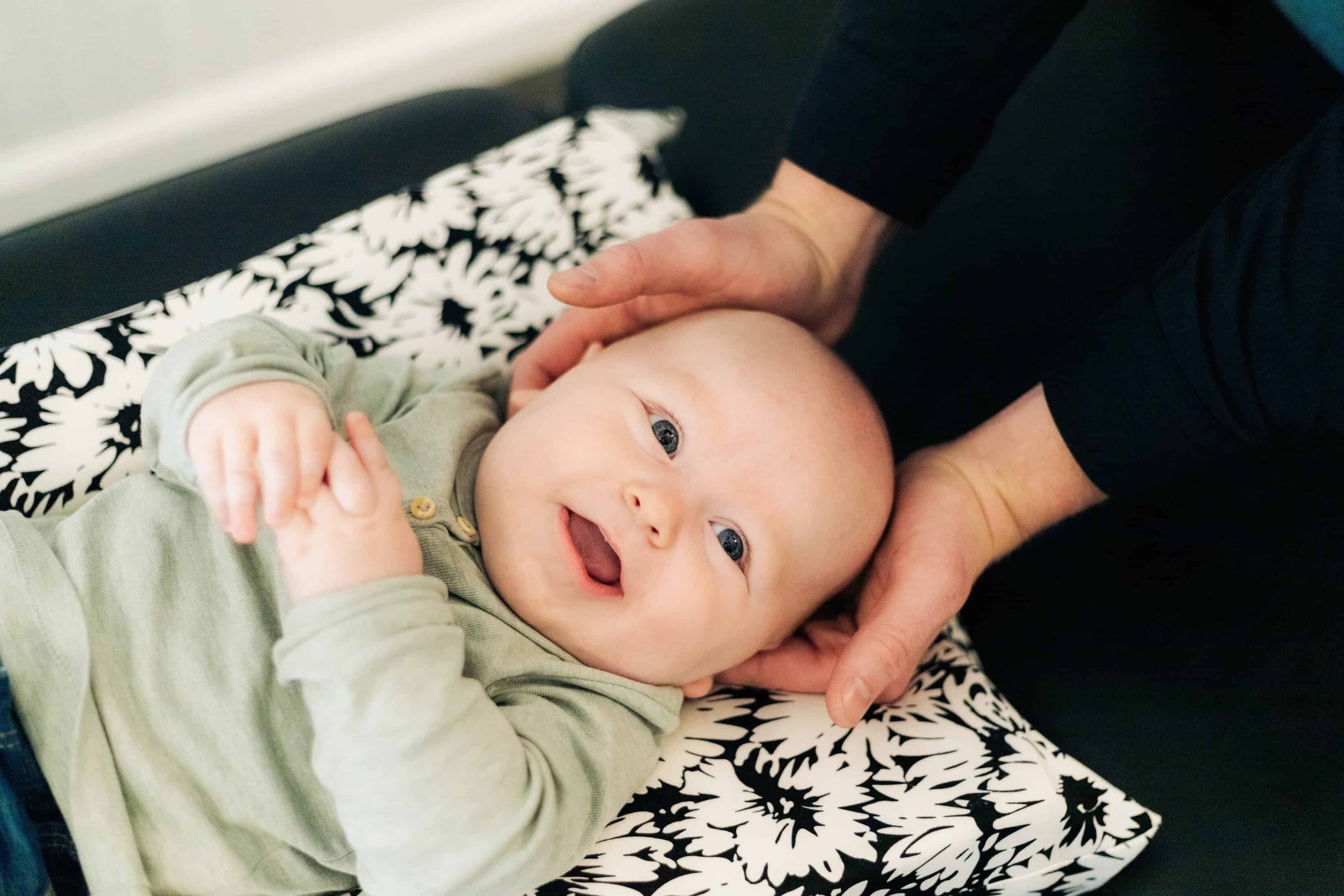 Photo of a newborn demonstrating baby chiropractor benefits while getting neck adjusted on a table