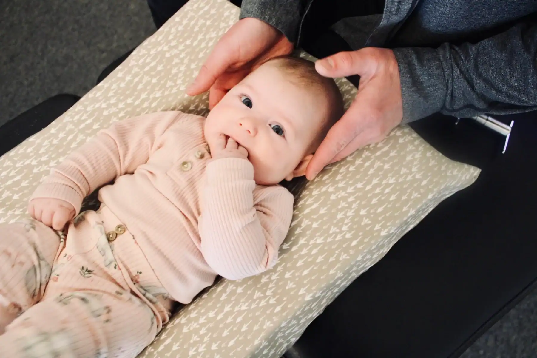 Photo of a newborn baby with oral tie getting neck adjusted by a chiropractor on a table