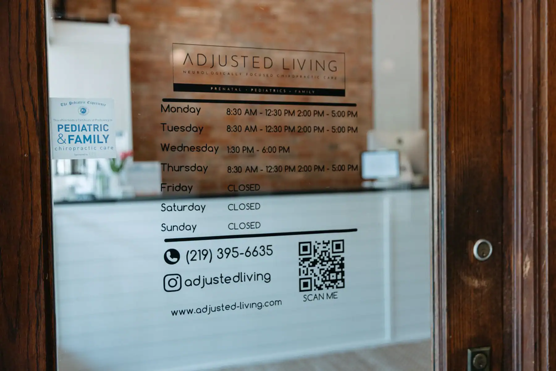 Photo of the Adjusted Living window decal with contact details and hours for treating signs of nervous system dysregulation