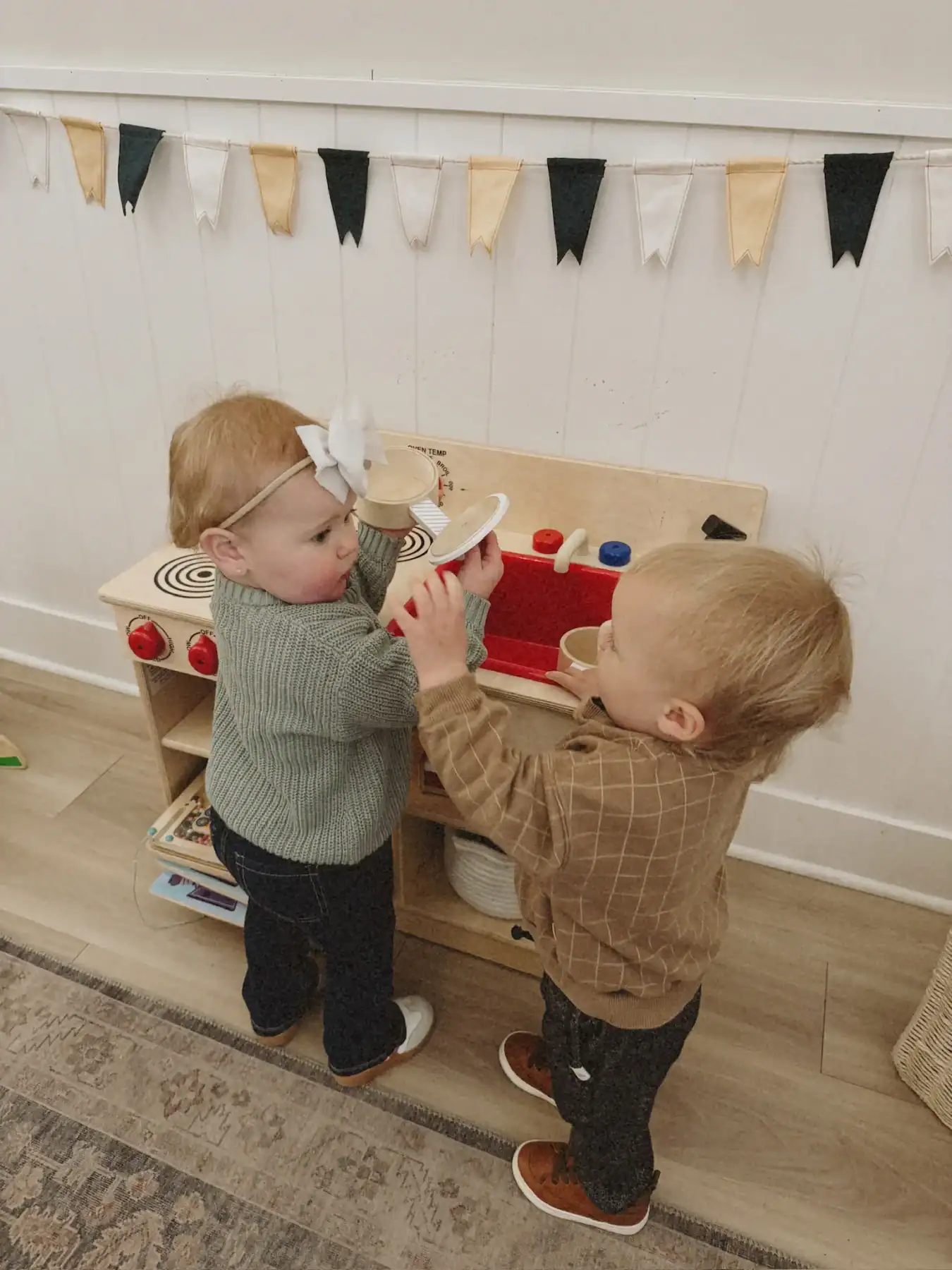 photo of two young toddlers playing with kitchen toys and looking concerned with back to school anxiety