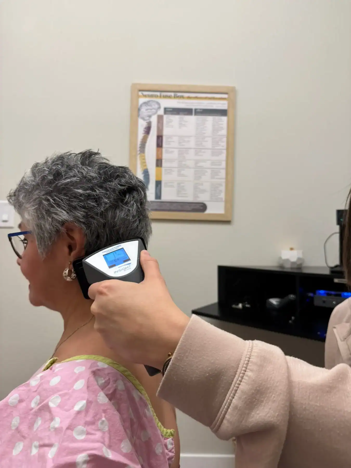 photo of a senior woman getting an INSiGHT scan by a chiropractor in a clinic