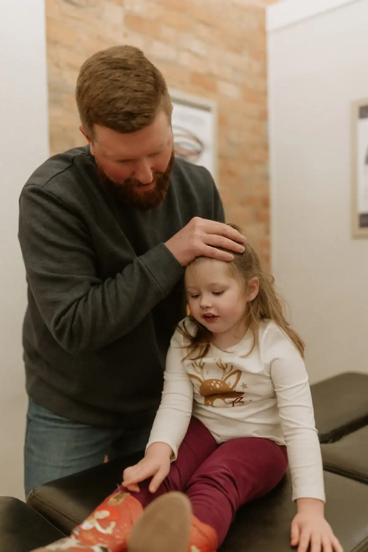 photo of chiropractor Dr. Ryan adjusting a young girl's neck as she sits on a bench